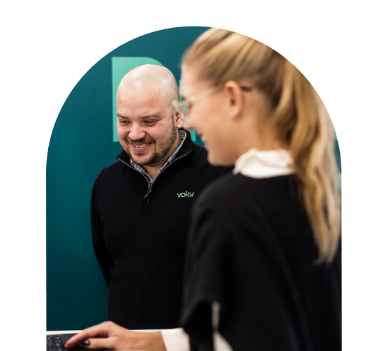 Tv&aring; leende Voky-anst&auml;llda som tittar ner p&aring; en dator